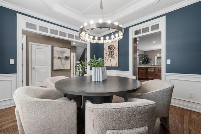 dining area featuring wood finished floors, a notable chandelier, ornamental molding, and a wainscoted wall