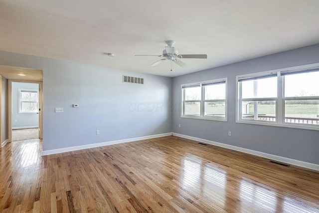 empty room featuring plenty of natural light, ceiling fan, and visible vents