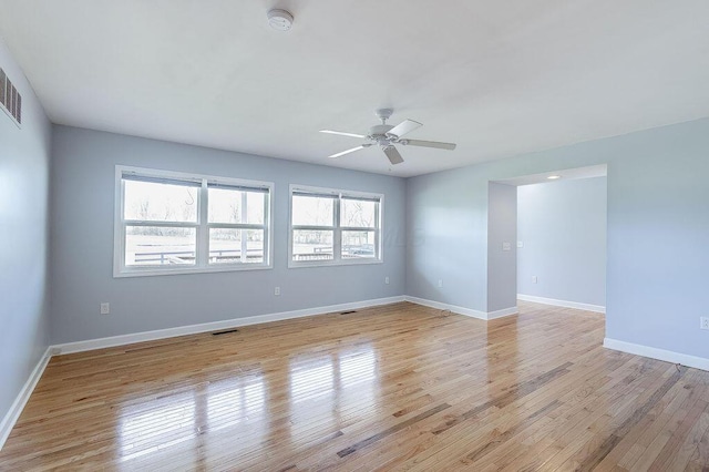 empty room featuring baseboards, ceiling fan, visible vents, and light wood-style flooring