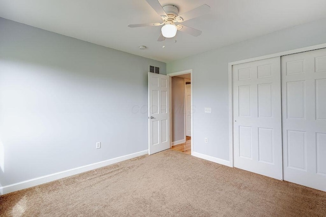 unfurnished bedroom with baseboards, a ceiling fan, a closet, and light carpet