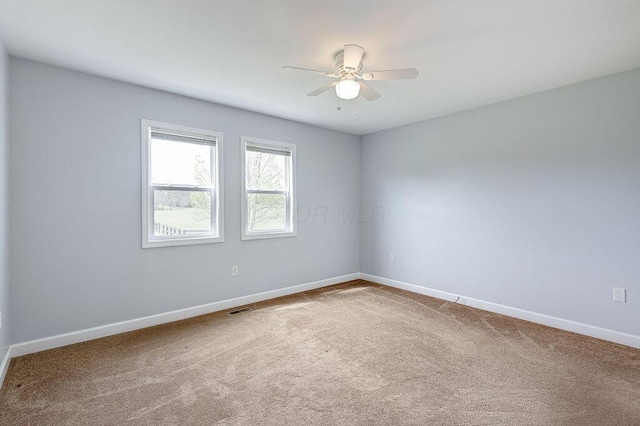 carpeted spare room featuring baseboards, ceiling fan, and visible vents