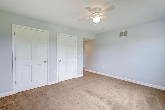 unfurnished bedroom with baseboards, carpet, a ceiling fan, and visible vents