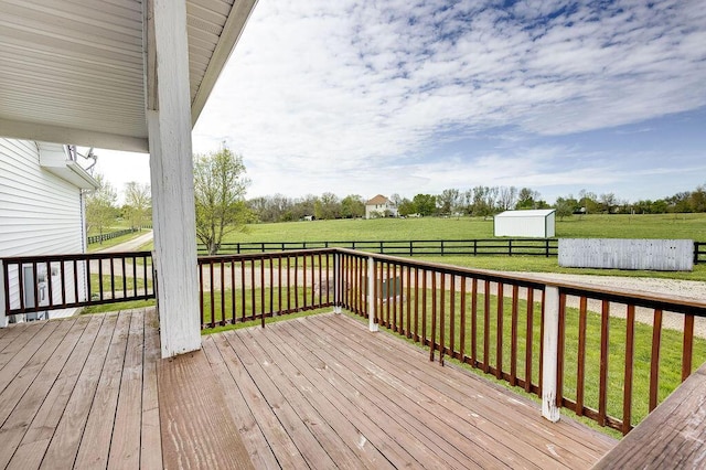 wooden terrace featuring an outdoor structure, a fenced backyard, a shed, a yard, and a rural view