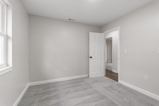 carpeted empty room featuring baseboards and visible vents