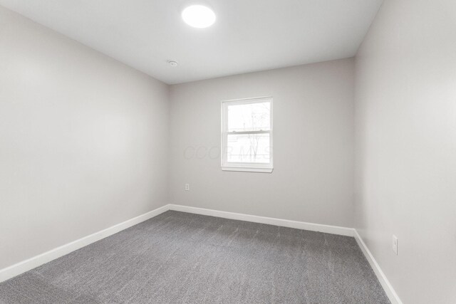 empty room with baseboards and dark carpet