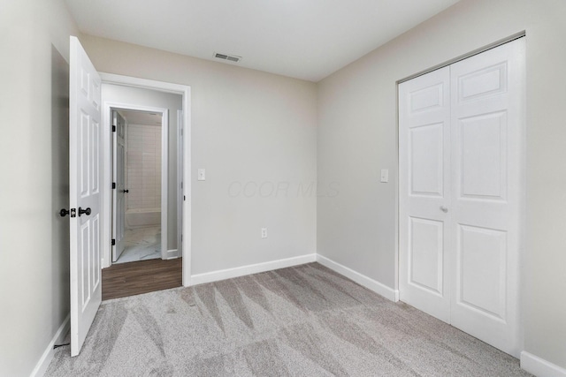 unfurnished bedroom featuring baseboards, visible vents, a closet, and carpet