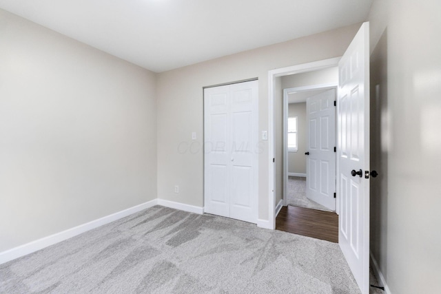 unfurnished bedroom with carpet flooring, a closet, and baseboards