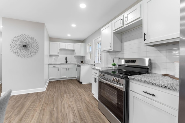 kitchen with white cabinetry, a sink, stainless steel appliances, and light wood-style floors