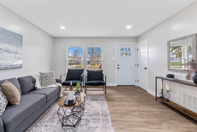 living room with light wood finished floors, baseboards, visible vents, and recessed lighting