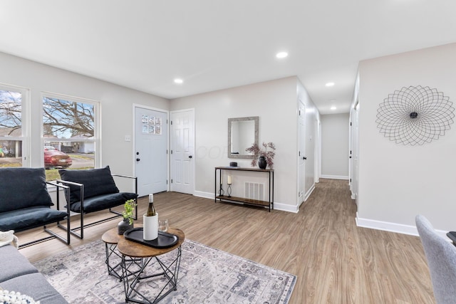 living area with baseboards, light wood-style flooring, and recessed lighting