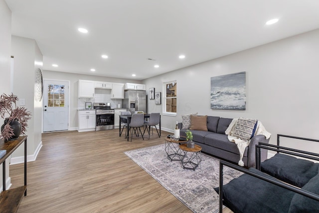 living room with light wood-style flooring, baseboards, and recessed lighting