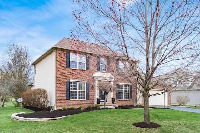 colonial house with stucco siding, a front yard, aphalt driveway, and an attached garage