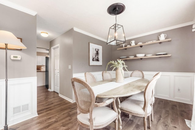 dining room featuring a wainscoted wall, wood finished floors, and ornamental molding