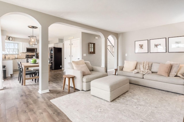 living room with light wood finished floors, baseboards, and arched walkways