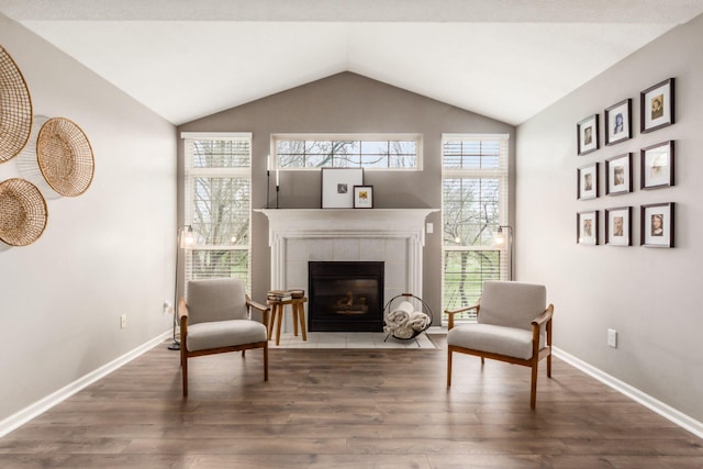 sitting room with baseboards, a fireplace, wood finished floors, and vaulted ceiling