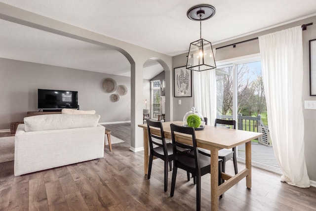 dining room with baseboards, wood finished floors, and arched walkways