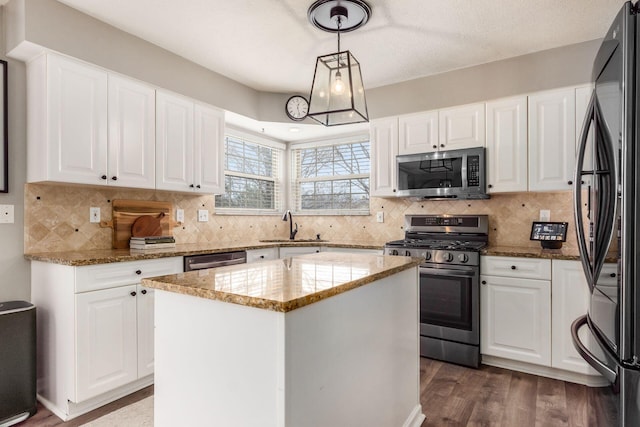 kitchen featuring white cabinetry, backsplash, a sink, light stone counters, and appliances with stainless steel finishes