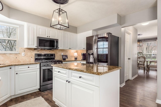 kitchen featuring stone counters, a kitchen island, appliances with stainless steel finishes, dark wood-style floors, and decorative backsplash