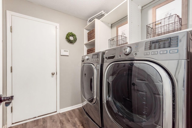 laundry room featuring a textured ceiling, independent washer and dryer, baseboards, wood finished floors, and laundry area