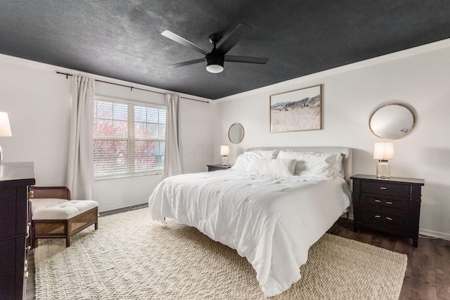 bedroom featuring crown molding, a ceiling fan, a textured ceiling, baseboards, and dark wood-type flooring