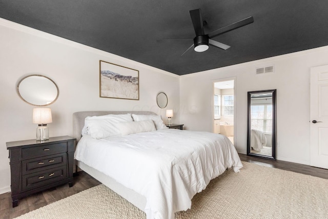 bedroom with dark wood-style flooring, visible vents, crown molding, a ceiling fan, and ensuite bath