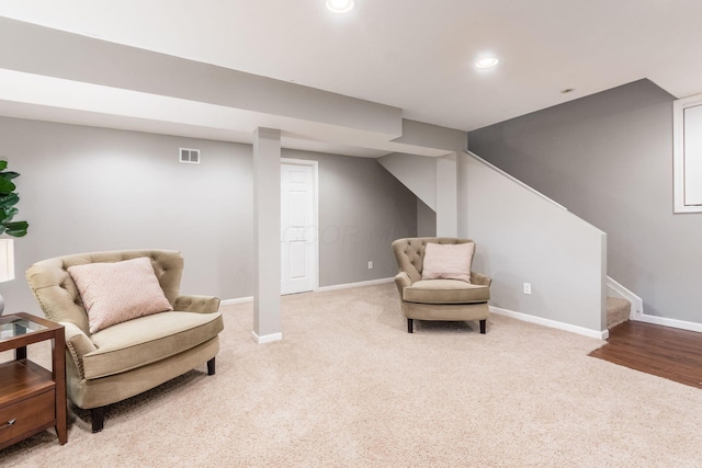 living area featuring light carpet, stairs, visible vents, and baseboards