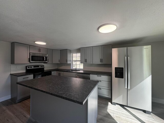 9808 Alderman Rd, Millfield, OH 45761 - kitchen with dark wood-style flooring, appliances with stainless steel finishes, a sink, gray cabinets, and a center island