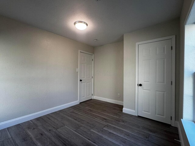9808 Alderman Rd, Millfield, OH 45761 - unfurnished bedroom featuring dark wood-type flooring, a textured ceiling, and baseboards