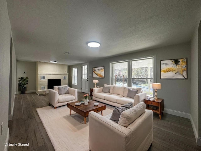 9808 Alderman Rd, Millfield, OH 45761 - living room featuring a fireplace, a textured ceiling, baseboards, and wood-type flooring
