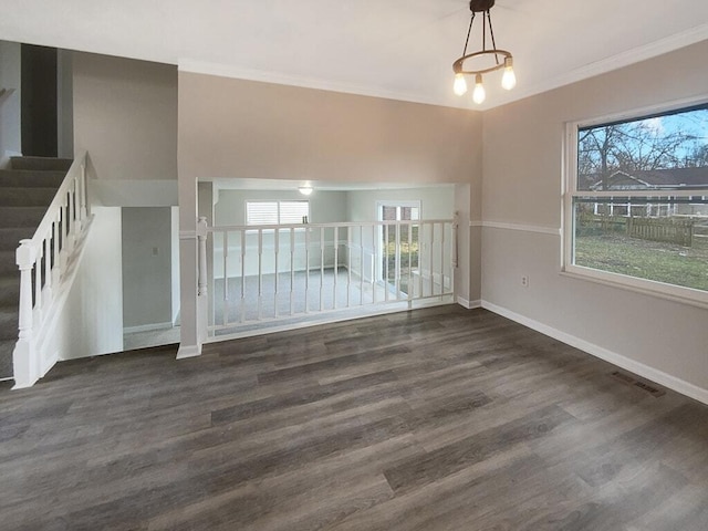 empty room featuring dark wood-style floors, ornamental molding, and a wealth of natural light