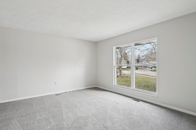 carpeted empty room with a textured ceiling, baseboards, and visible vents
