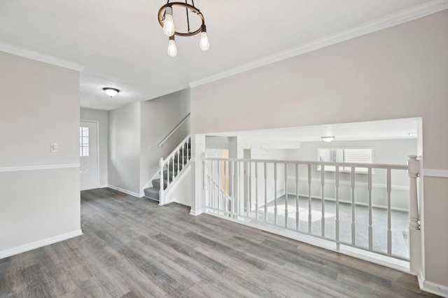 unfurnished room with crown molding, baseboards, a chandelier, and wood finished floors