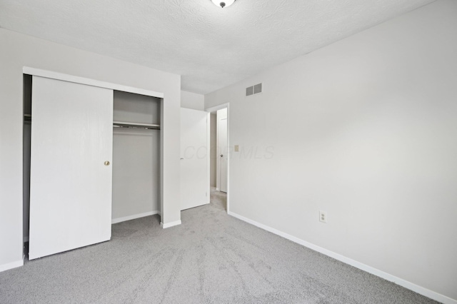 unfurnished bedroom featuring carpet flooring, baseboards, a textured ceiling, visible vents, and a closet
