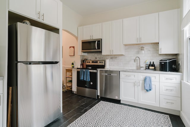 kitchen with stainless steel appliances, white cabinetry, a sink, and decorative backsplash