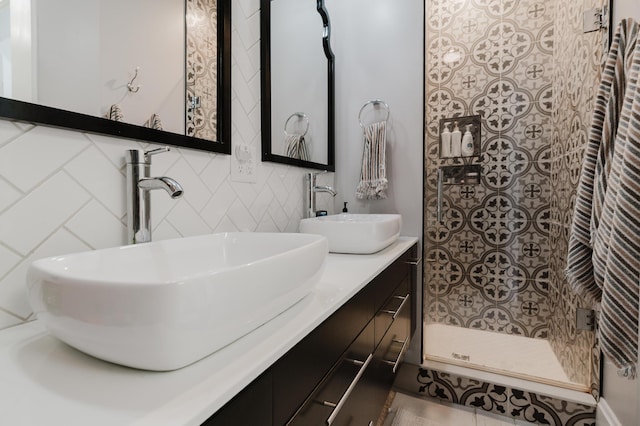 full bath featuring double vanity, a tile shower, a sink, and backsplash