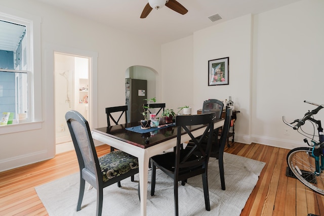 dining room with baseboards, visible vents, ceiling fan, arched walkways, and wood finished floors