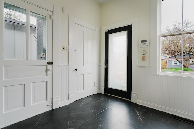 foyer entrance featuring wainscoting and marble finish floor