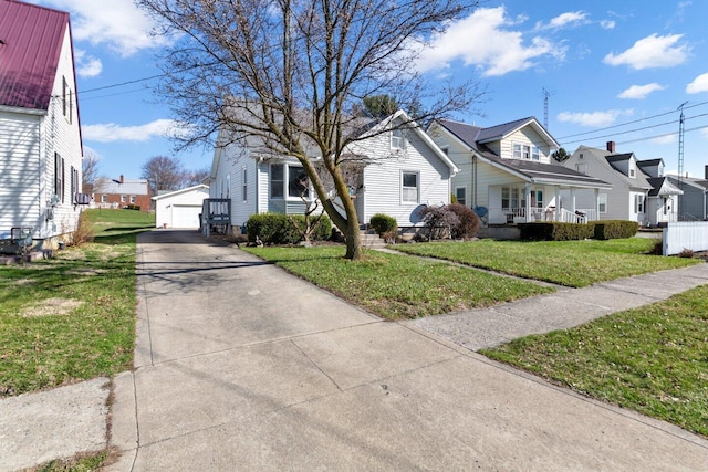 view of side of property featuring a lawn, a detached garage, an outdoor structure, and a residential view
