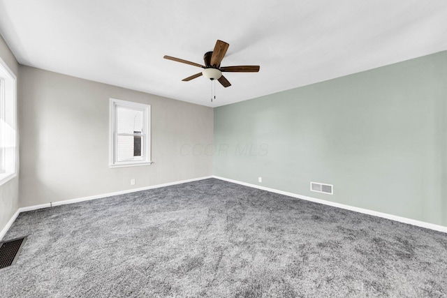 carpeted spare room with baseboards, ceiling fan, and visible vents
