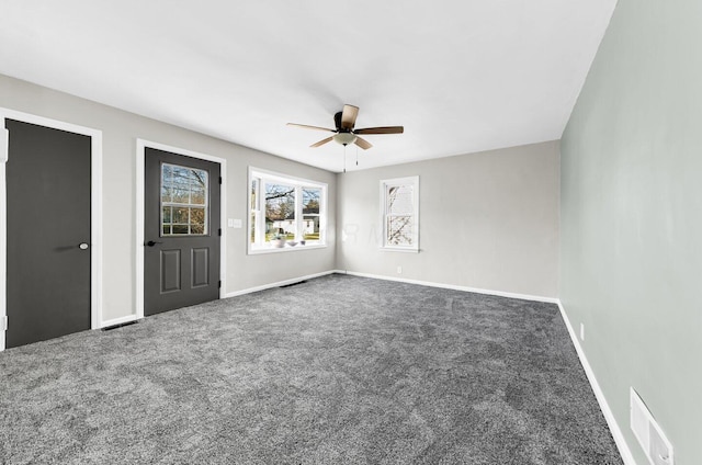 carpeted spare room featuring baseboards, visible vents, and a ceiling fan