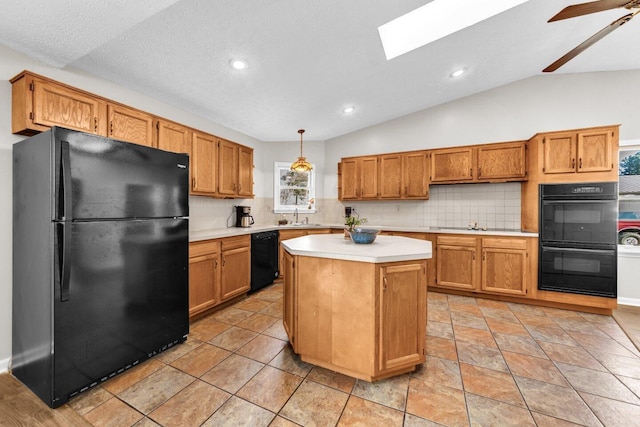 kitchen featuring light countertops, vaulted ceiling with skylight, tasteful backsplash, a sink, and black appliances
