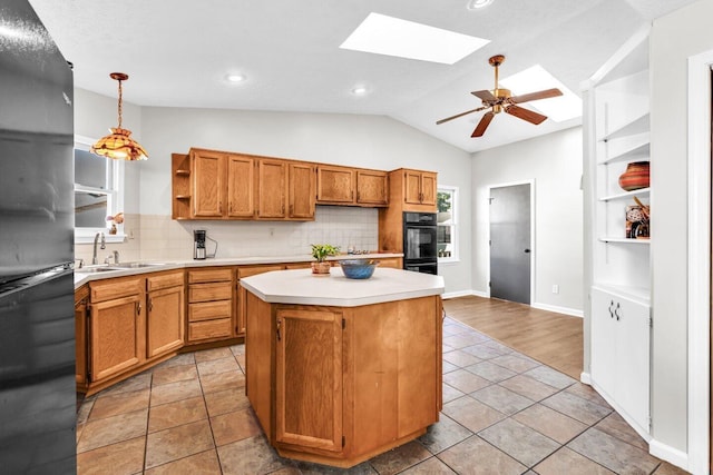 kitchen with vaulted ceiling with skylight, light countertops, a sink, freestanding refrigerator, and open shelves