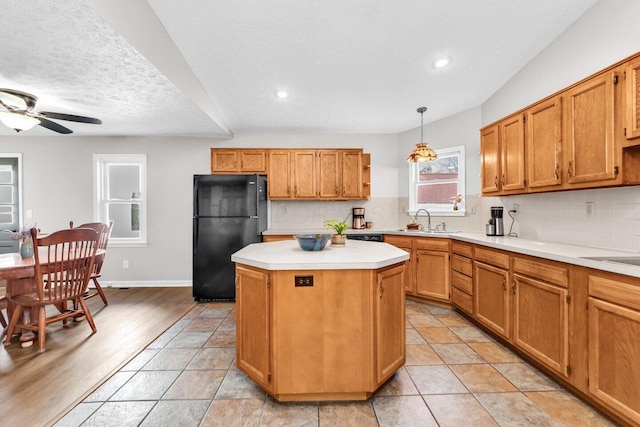 kitchen with a kitchen island, tasteful backsplash, a sink, and freestanding refrigerator