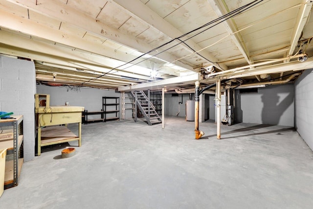 unfinished below grade area featuring heating unit, gas water heater, and stairs