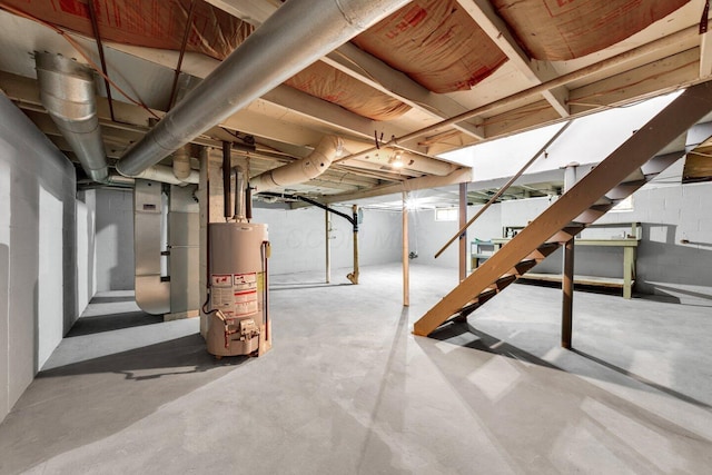 unfinished basement featuring heating unit, stairway, and gas water heater