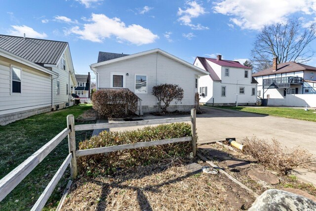 view of side of home with a lawn, fence, concrete driveway, and a residential view