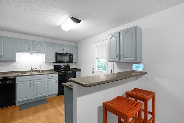 572 Sycamore Dr, Pickerington, OH 43147 - kitchen featuring black appliances, a sink, dark countertops, a peninsula, and a breakfast bar area