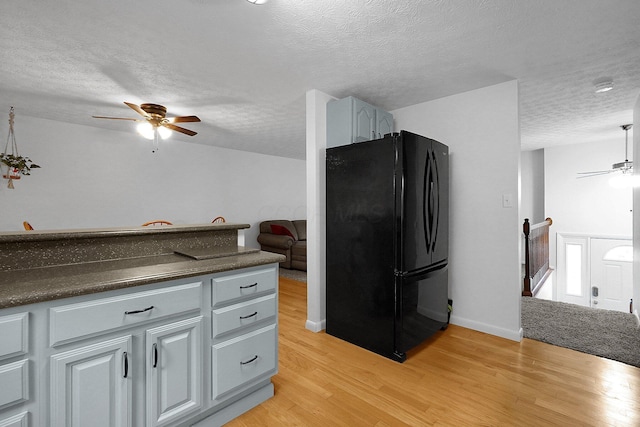 572 Sycamore Dr, Pickerington, OH 43147 - kitchen with freestanding refrigerator, a ceiling fan, a textured ceiling, light wood finished floors, and dark countertops