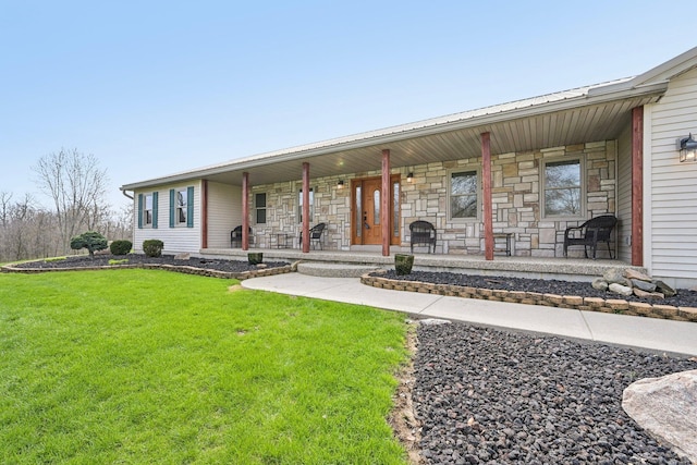 view of front of home featuring a front yard, metal roof, stone siding, and covered porch