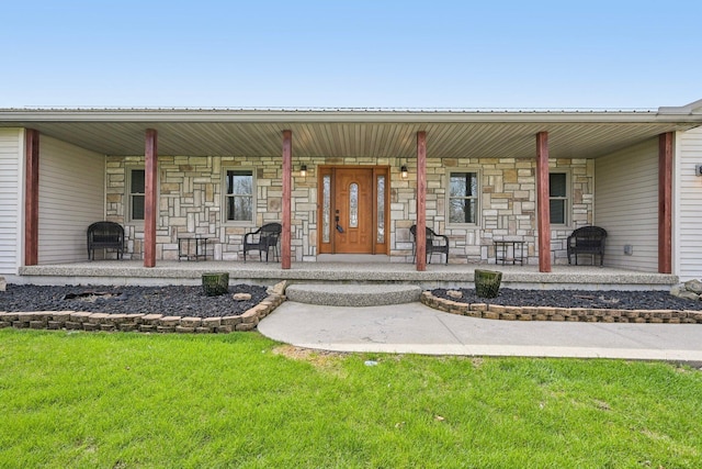 doorway to property with a yard, stone siding, and covered porch